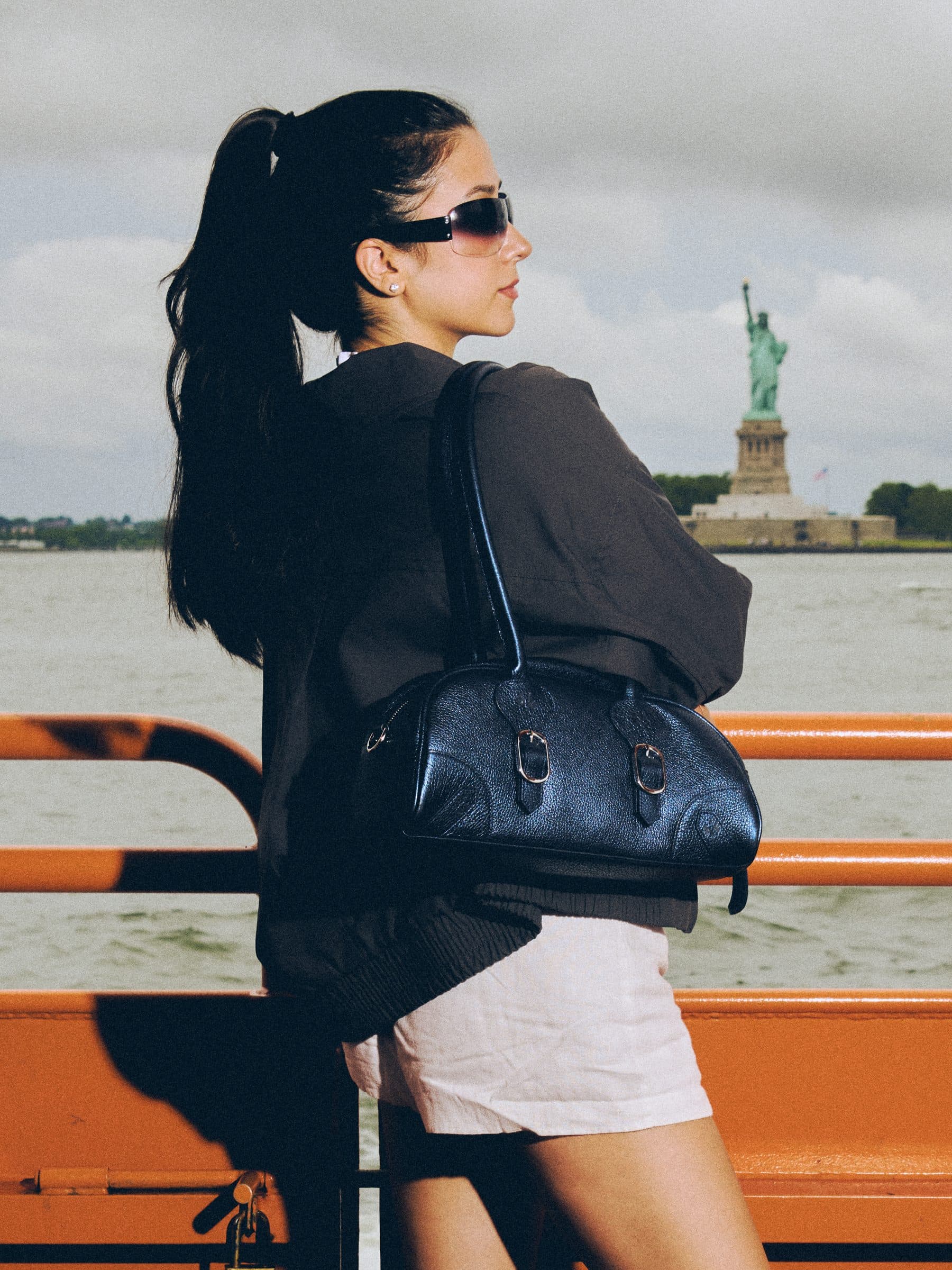 Model on the ferry with the Navy Gammon Bag, Statue of Liberty behind