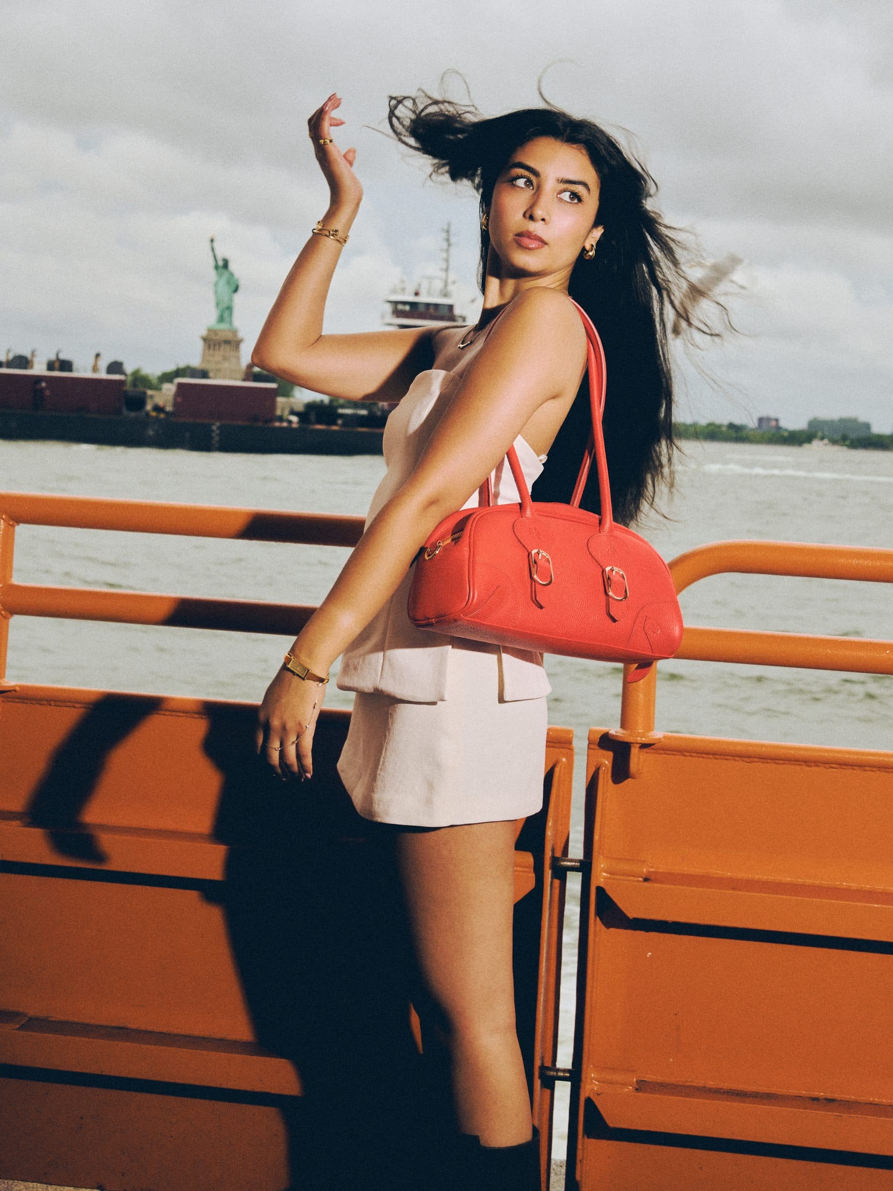 Model on the ferry with the Orange Gammon Bag, Statue of Liberty behind